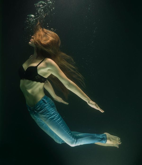Woman in a graceful yoga pose in a dark room with electric blue light trails.